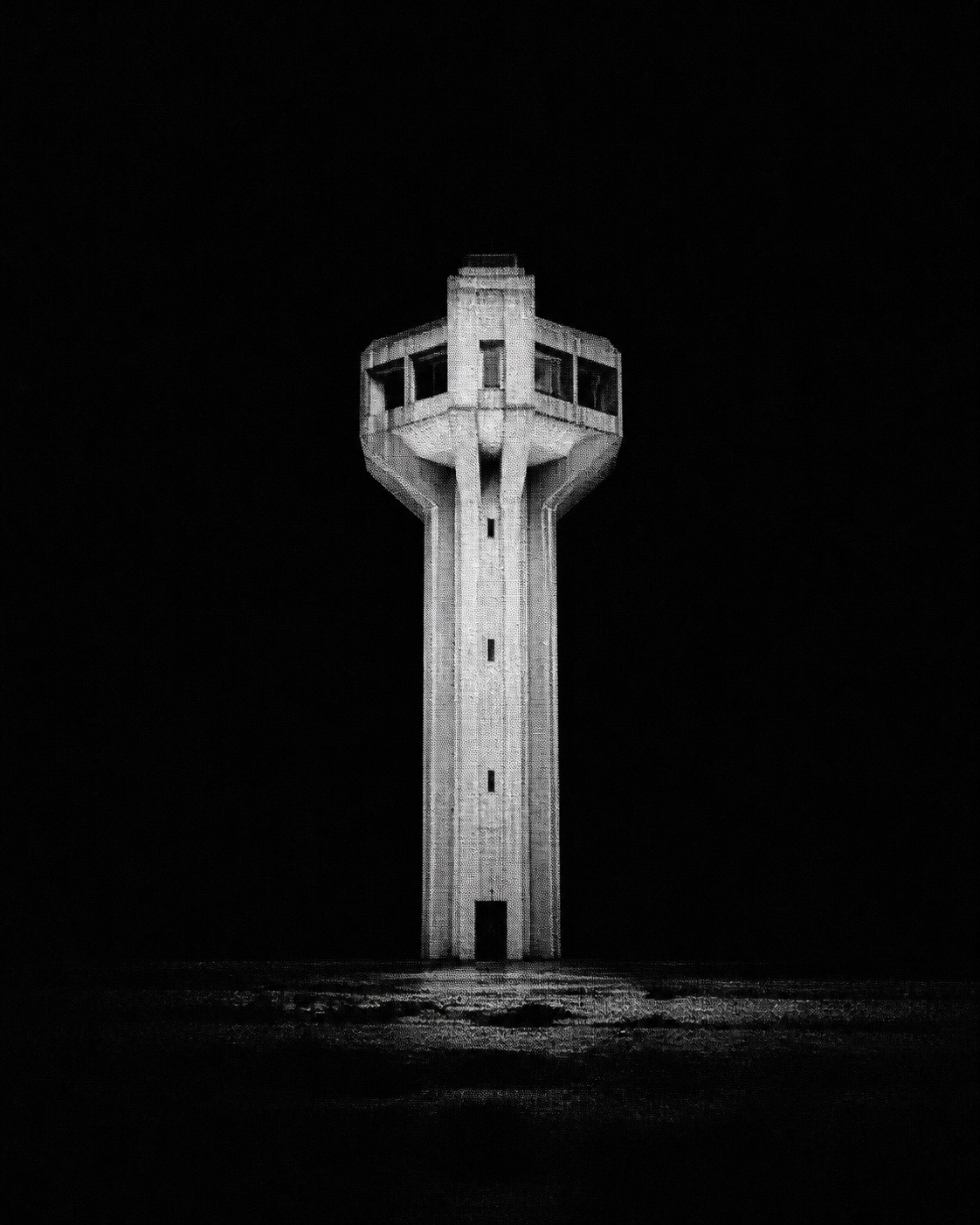 An isolated concrete observation tower in a dark landscape